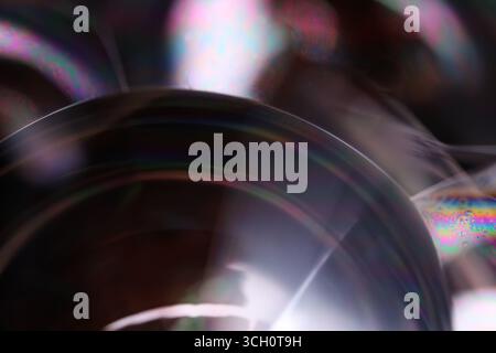 Plan macro d'un bord de bulle de savon avec couleurs arc-en-ciel irisées et mouvement liquide sur fond noir Banque D'Images