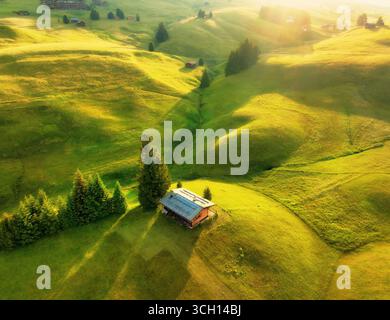 Vue aérienne des prairies alpines verdoyantes avec des maisons sur les collines Banque D'Images
