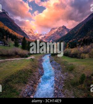 Ruisseau dans la vallée de montagne avec des arbres d'automne, pic enneigé au coucher du soleil Banque D'Images