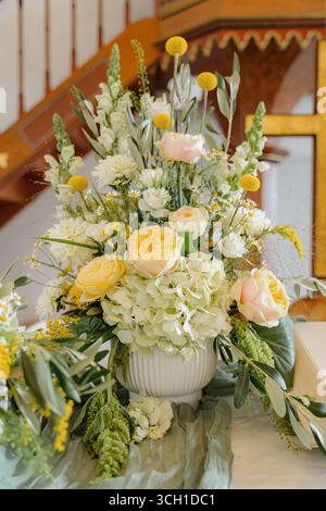 Élégant arrangement floral avec des roses jaunes et blanches avec de la verdure dans un vase blanc. Parfait pour les mariages, les événements et la décoration de la maison, en ajoutant un Banque D'Images