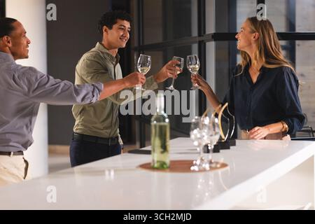 Griller avec des verres à vin, divers collègues célébrant lors d'une réunion de bureau moderne Banque D'Images