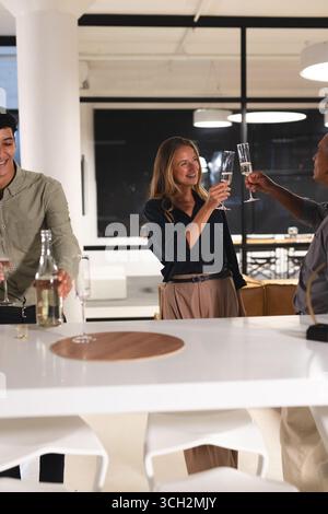Divers collègues célèbrent le succès avec du champagne dans un bureau moderne la nuit Banque D'Images