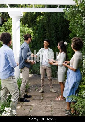 Rassemblement en plein air, amis échangeant des salutations et parler au jardin petit événement de mariage décontracté Banque D'Images