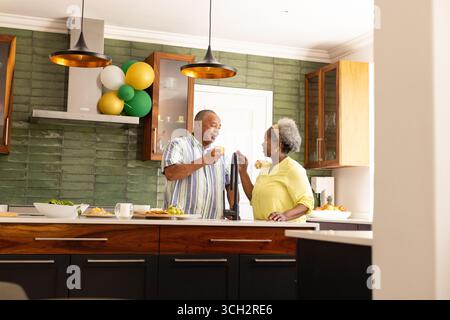 Couple senior appréciant le petit déjeuner ensemble dans la cuisine moderne, souriant et bavardant Banque D'Images