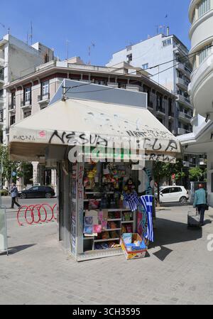 Thessalonique, Grèce-avril 23,2025:personnes non identifiées marchant par le petit kiosque coloré avec drapeaux grecs sur la rue Banque D'Images