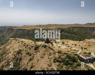 Vue aérienne de l'église de Vahramashen au sommet d'une crête cuite au soleil, ses pierres anciennes contrastant avec les prairies ocres, église de Vahramashen, province d'Aragatsotn, Arménie. Banque D'Images