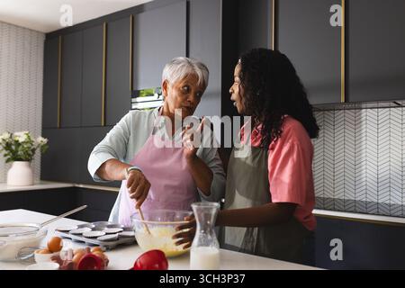Mère aînée et fille adulte cuisinant dans une cuisine moderne, partageant des recettes, à la maison Banque D'Images