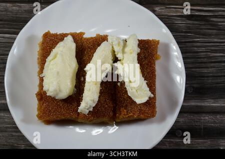 Basbosa au lait crémeux laitier qeshta crémeux coagulé et saturé de sirop sucré de miel, Basbusa est un dessert du moyen-Orient qui est généralement du bak Banque D'Images