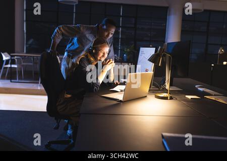 Collaborant sur le projet, les collègues se sont concentrés sur l'écran d'ordinateur dans le bureau travaillant tard Banque D'Images