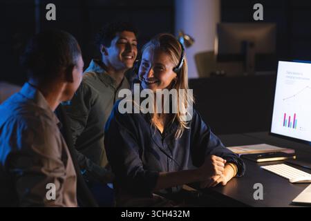 Équipe collaborant au bureau, souriant et discutant des données sur l'écran de l'ordinateur Banque D'Images