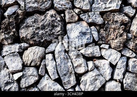 Mur en pierre naturelle présentant des roches irrégulières et texturées, soulignant la robustesse et un environnement rustique. Parfait pour les arrière-plans ou le design naturel Banque D'Images