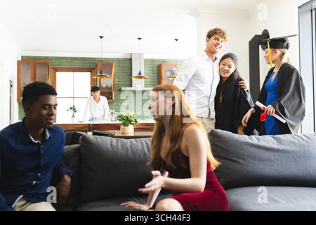 Adolescents célébrant la remise des diplômes à la maison, souriant et profitant du temps avec des amis Banque D'Images