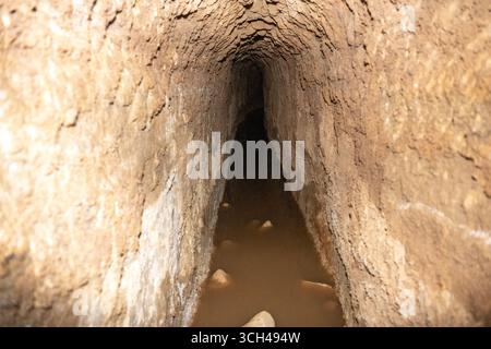Un étroit tunnel d'aqueduc souterrain romain avec un sol humide et boueux et des murs rocheux à Mérida, Espagne Banque D'Images