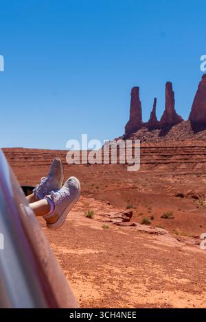 Pieds avec des baskets sur la fenêtre de la voiture avec Monument Valley en arrière-plan Banque D'Images