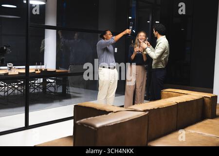Collègues célébrant le succès avec un verre dans un bureau moderne la nuit Banque D'Images