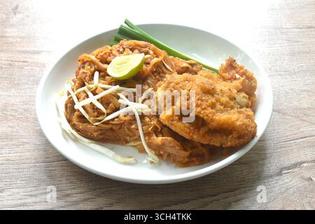 Pad Thaï nouilles de riz sautées avec crevettes sèches et garniture d'oeuf poulet frit croustillant sur l'assiette Banque D'Images