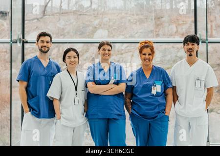 Portrait de professionnels médicaux masculins et féminins souriants multiraciaux debout côte à côte dans le couloir de l'hôpital Banque D'Images