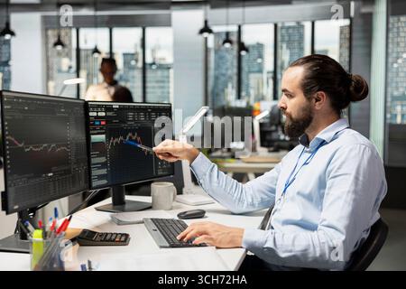 Analyste de risque examinant l'interface des graphiques en chandelier pour identifier les signes de volatilité du marché. Homme regardant les graphiques à l'écran, examinant les rapports de performance du portefeuille, vérifiant les risques financiers Banque D'Images
