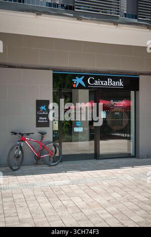 Viladecans. Barcelone - 31 août 2025 : vue rapprochée de l'entrée d'une succursale de CaixaBank. L'image montre l'identité de marque de la banque, y compris i Banque D'Images