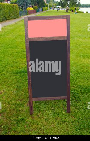 Panneau de menu de tableau noir vide debout sur le champ d'herbe dans le parc, fournissant de l'espace pour la publicité ou les annonces Banque D'Images