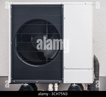 Ventilateur de pompe à chaleur moderne avec une grille protégeant les pales rotatives, installé sur le mur extérieur d'un bâtiment Banque D'Images