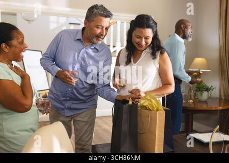 Divers amis seniors célébrant à la maison, échangeant des cadeaux et dégustant des boissons ensemble. Célébration, amitié, fête, bonheur, rassemblement, des vies Banque D'Images