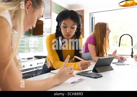Des adolescentes collaborent sur un projet scolaire à la maison, en utilisant une tablette et des notes Banque D'Images