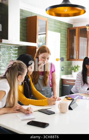 Des adolescentes collaborent sur un projet scolaire à la maison, en utilisant une tablette et des notes Banque D'Images