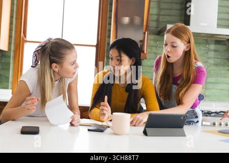 Des adolescentes collaborent sur un projet scolaire à la maison, en utilisant une tablette et des notes Banque D'Images