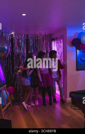 Adolescents célébrant à la maison avec des ballons et boule disco, profitant de la fête ensemble Banque D'Images
