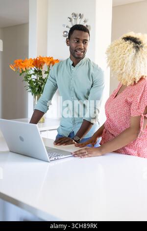 Amis collaborant sur ordinateur portable dans la cuisine moderne, discutant des idées de projet Banque D'Images