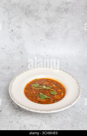 Soupe traditionnelle de haricots géorgiens Lobio avec des herbes dans une assiette en céramique Banque D'Images