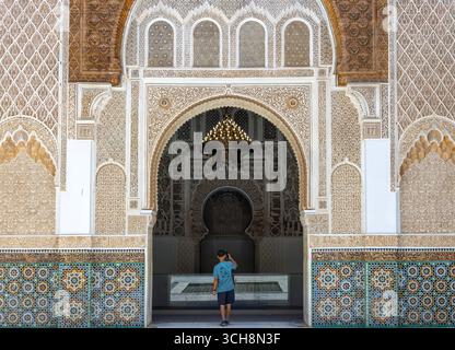 Stuc sculpté et frise de cèdre avec calligraphie arabe et petites fenêtres cintrées sur le mur de la cour de Ben Youssef Madrasa (Medersa Ben Youssef) Banque D'Images