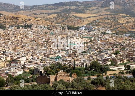 Vue panoramique sur la médina de Fès (Fès), Maroc, depuis un belvédère à flanc de colline, montrant des toits denses, des minarets de mosquées et les collines environnantes. Banque D'Images