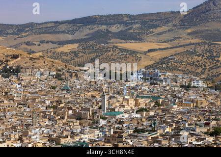 Vue panoramique sur la médina de Fès (Fès), Maroc, depuis un belvédère à flanc de colline, montrant des toits denses, des minarets de mosquées et les collines environnantes. Banque D'Images