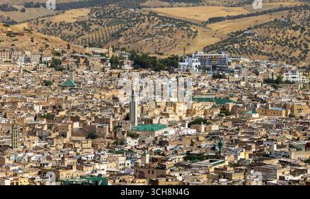 Vue panoramique sur la médina de Fès (Fès), Maroc, depuis un belvédère à flanc de colline, montrant des toits denses, des minarets de mosquées et les collines environnantes. Banque D'Images
