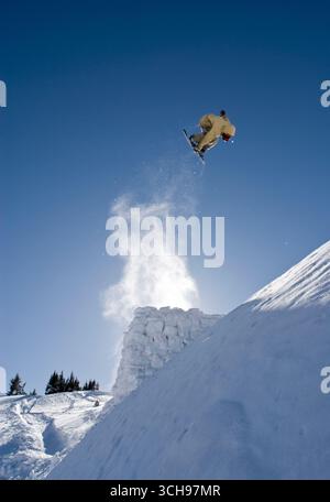Snowboarder qui tourne après un saut dans l'arrière-pays du Colorado. Banque D'Images