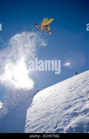 Snowboarder qui tourne après un saut dans l'arrière-pays du Colorado. Banque D'Images