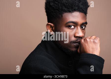 Gros plan d'un homme africain en veste noire regardant la caméra isolée Banque D'Images