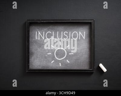 Tableau noir avec le mot inclusion et un dessin solaire promouvant l'égalité, la diversité et la tolérance Banque D'Images