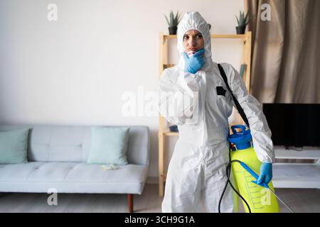 Exterminateur féminin du service de lutte antiparasitaire travaillant à l'intérieur de la maison avec bouteille de pulvérisateur pensant au problème à la maison. copier l'espace Banque D'Images