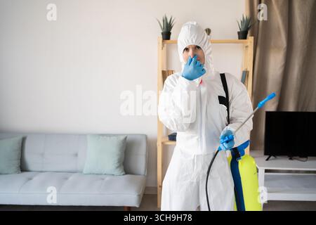Exterminateur féminin du service de lutte antiparasitaire travaillant à l'intérieur de la maison couvrant le nez avec l'expression de dégoût à la maison. copier l'espace Banque D'Images