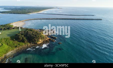 Vue aérienne du phare debout sentinelle sur la côte accidentée où la rivière rencontre le vaste océan, Port Macquarie, Nouvelle-Galles du Sud, Australie. Banque D'Images