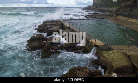 Vue aérienne des vagues qui s'écrasent et les eaux calmes et calmes de la piscine de North Narrabeen Rock Pool créent un contraste fascinant, North Narrabeen, Nouvelle-Galles du Sud, Australie. Banque D'Images