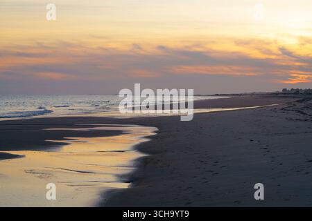 Rivage paisible avec des vagues douces et un ciel de coucher de soleil brillant. Banque D'Images