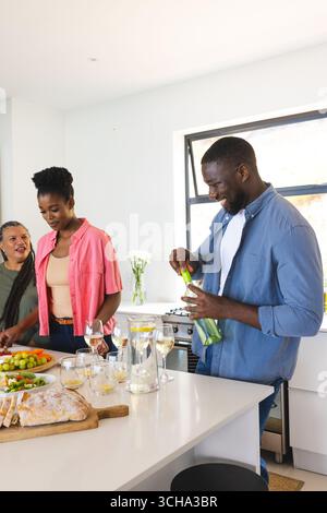 Amis préparant des boissons et appréciant la conversation dans une cuisine lumineuse et moderne. Socialisation, amitié, style de vie, cuisine, boisson, décontracté Banque D'Images