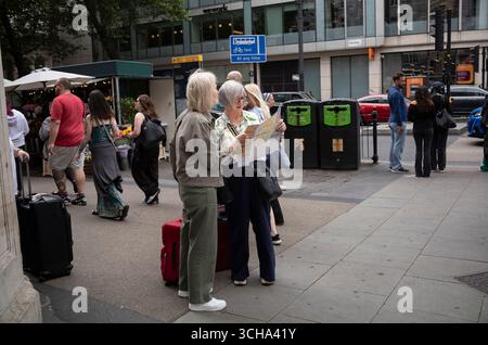 Touristes d'âge moyen regardant une carte des rues de la région tout en s'arrêtant à un coin de rue dans le centre de Londres, Angleterre, Royaume-Uni Banque D'Images