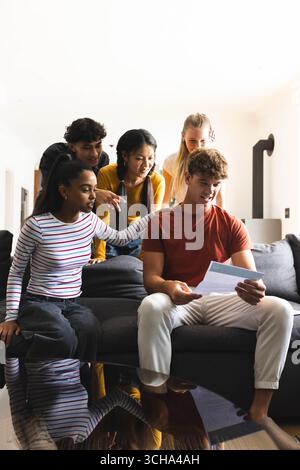 Adolescents divers célébrant les résultats des examens ensemble à la maison, souriant et encourageant avec enthousiasme. Célébration, réalisation, succès, bonheur, étudiants, f Banque D'Images