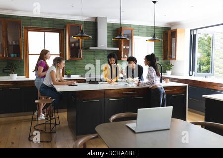 À l'école, adolescents divers amis discutant du projet avec enthousiasme et travail d'équipe dans la cuisine, à la maison. Collaboration, amitié, brainstorming, studyin Banque D'Images