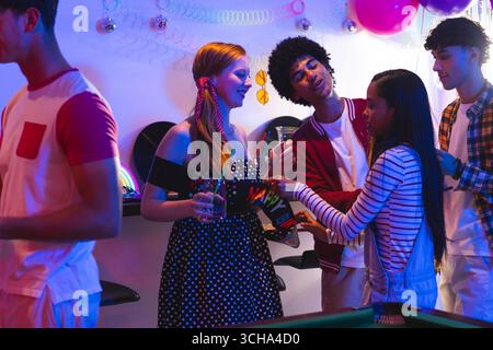 Adolescents divers célébrant à la fête, appréciant la musique et socialisant avec divers amis, à la maison. célébration, vie nocturne, danse Banque D'Images